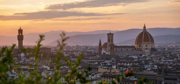 An old city with a cathedral dome at sunset